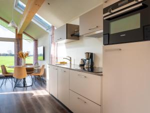 a kitchen with white cabinets and a table with chairs at Eco Holiday Home - Airco & Panoramisch uitzicht - Achterhoek in Almen