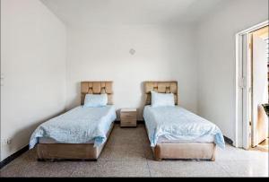 two beds in a room with white walls at Villa à harhora in Temara