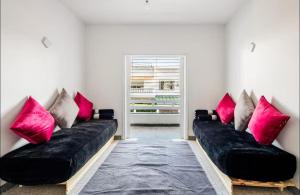 a living room with two black couches with pink pillows at Villa à harhora in Temara