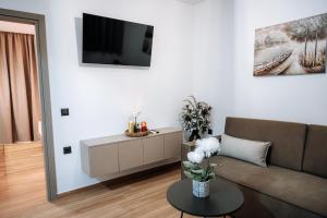 a living room with a couch and a tv on a wall at ILIADA Boutique Rooms in Faliraki