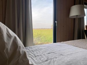 a bedroom with a bed and a window with a field at Studio op Camperplaats Vechtdal in Nieuwleusen +2 photos