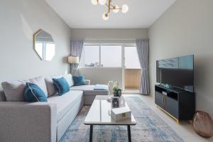a living room with a couch and a tv at Urban Chic - Marina Bay in Abu Dhabi