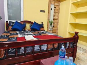 a wooden bed with blue pillows and a bottle of water at Ocean Wind Homestay in Pondicherry