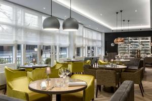a restaurant with tables and yellow chairs and windows at NH Bussum Jan Tabak in Bussum