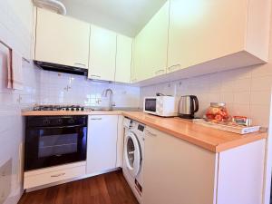a kitchen with white cabinets and a washer and dryer at Casa Petrucci 2 centro storico, accesso ztl e park gratuito in Forlì +9 photos