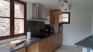 a kitchen with wooden cabinets and a black counter top at Murmures de Loire in Montjean-sur-Loire