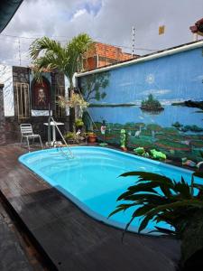 a swimming pool with a mural on the side of a building at Chalé Santarém, located in Mosqueiro! in Belém