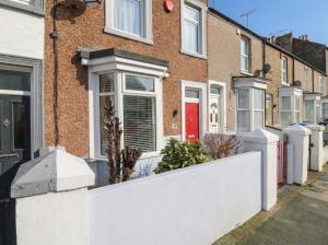 a white fence in front of a brick house at Meregate Cottage in Margate