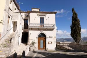 a white house with a wooden door and a balcony at Locanda Severino in Caggiano