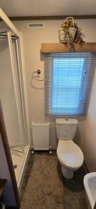 a bathroom with a toilet and a shower and a window at CJ's Happy Place in Heysham +31 photos