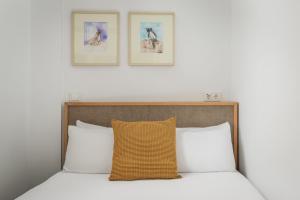 a bed with two white pillows and two pictures on the wall at BYPILLOW Tiento in Cádiz