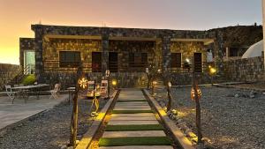 a building with a pathway in front of it with lights at Shahad Guest House in Jebel Shams