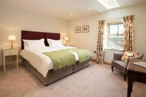a bedroom with a bed and a chair and a window at Old Granary House in Chesters