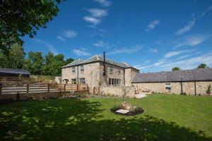 an old stone building with a fence and a yard at Old Granary House in Chesters