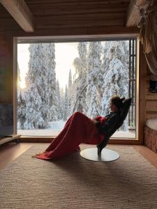 a woman sitting on a table in front of a window at Handcrafted Log Chalet Villa Aarreaitta in Syöte