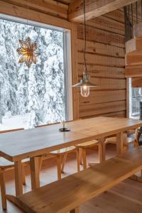 a dining room with a wooden table and a large window at Handcrafted Log Chalet Villa Aarreaitta in Syöte