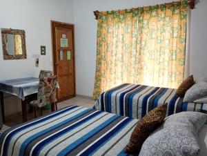 a room with two beds and a desk and a window at Pension Baja Paradise in La Paz