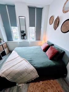 a bedroom with a green bed with pillows on it at L'Emile Zola in Saint-Quentin