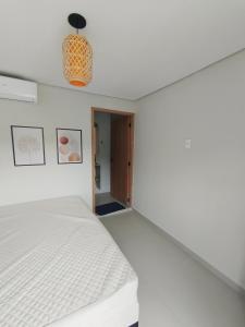 a bedroom with a white bed and a pendant light at Enseada Beach in São Sebastião +1 photo