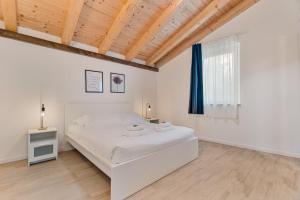 a white bedroom with a white bed and a blue curtain at Il Parco Apartment- Nature & Relax-Road To 5Terre in Beverino
