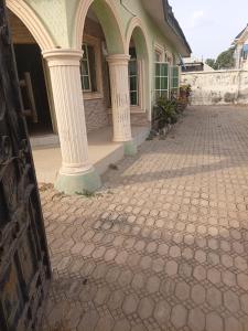 a building with two columns on a brick sidewalk at Limelight Apartment and suites in Oko Erin