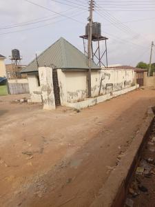 a dirt road next to a building with a water tower at Limelight Apartment and suites in Oko Erin
