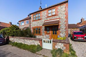 a red car parked in front of a brick house at 3 Bed in Bodham oc-1sfc in Bodham