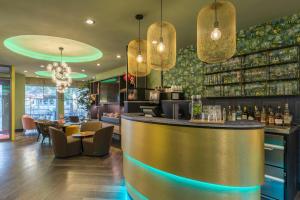 a bar in a restaurant with a counter and chairs at Leonardo Hotel Antwerpen in Antwerp