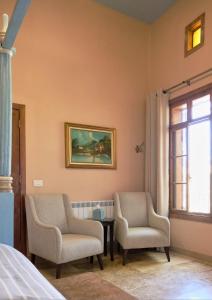 two chairs and a table in a room with a window at Spiritu in Ḩārat al Qal‘ah
