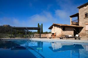 a large swimming pool next to a stone building at Masia Lledó de Trascastell in Balsareny
