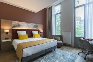 a bedroom with a large bed with yellow pillows at Leonardo Hotel Antwerpen in Antwerp