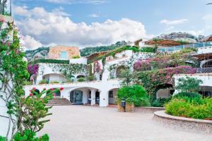 a white building with flowers on the side of it at Poltu Quatu House in Porto Cervo