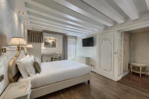 ein weißes Schlafzimmer mit einem Bett und einem Tisch in der Unterkunft Hotel Olimpia Venice, BW Signature Collection 3sup in Venedig