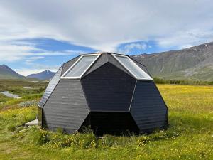 a small house sitting in a field of grass at Igloo-Dome by a River - Sky Sighting - Glamping in Litli-Árskógssandur