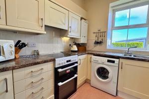a kitchen with a washing machine and a window at Seacrest Cottage in Conwy +3 photos