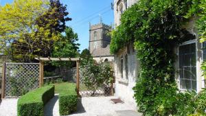 an old building with a gate and a church at Rose Cottage, Rodborough in Stroud