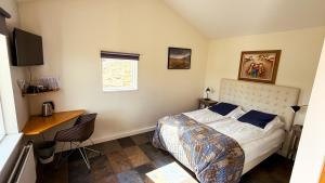 a bedroom with a bed and a desk and a window at Fossatún Country Hotel in Fossatún