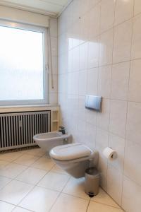 a bathroom with a toilet and a sink and a window at Kaiserviertel Gastromeile, City, Messe & Stadionnah in Dortmund