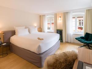 a bedroom with a large white bed and a chair at Relais et Châteaux Le Chambard in Kaysersberg
