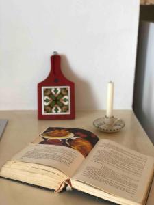 an open book on a table with a candle and a clock at Janela Blue Civico 35 in Otranto