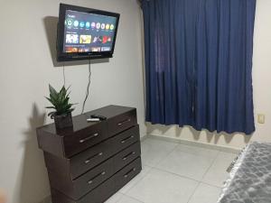 a bedroom with a dresser and a tv on the wall at Don Charlie in Veracruz