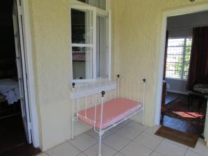 a bed sitting in a room with a window at Absolute Leisure Cottages in Machadodorp
