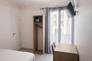 a bedroom with a bed and a tv and a window at Hotel Montana Paris Lafayette in Paris