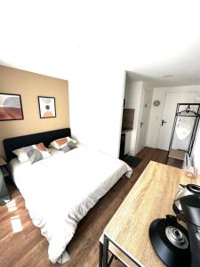 a bedroom with a large white bed and a desk at L'Emile Zola 2 in Saint-Quentin