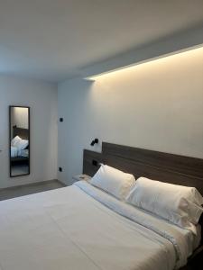 a bedroom with a large white bed and a mirror at Casa L'Oliver in Limone sul Garda