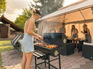 a woman is cooking food on a grill at Fotuso House in Majdany Wielkie