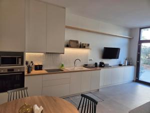 a kitchen with white cabinets and a wooden table at Karatza's suite 2 in Chios +4 photos