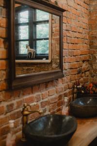 a bathroom with two sinks and a mirror with a dog in a window at Apartament w Zabytkowej Stajni nad Jeziorem z Dostępem do Parku i Sąsiedztwem XIX wiecznego Dworku Modrzewiowego in Szteklin +105 photos