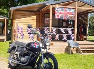 a motorcycle parked in front of a cabin with british flags at Chalet 3 étoiles - Piscine - ccbbgcc in Sauxillanges