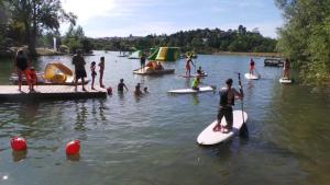 a group of people on surfboards in the water at ZEcamping 3 dog friendly avec piscine au bord du lac de la Thésauque in Nailloux